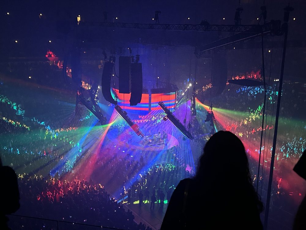 View of a concert arena lit by colorful lasers and a crowd of lights